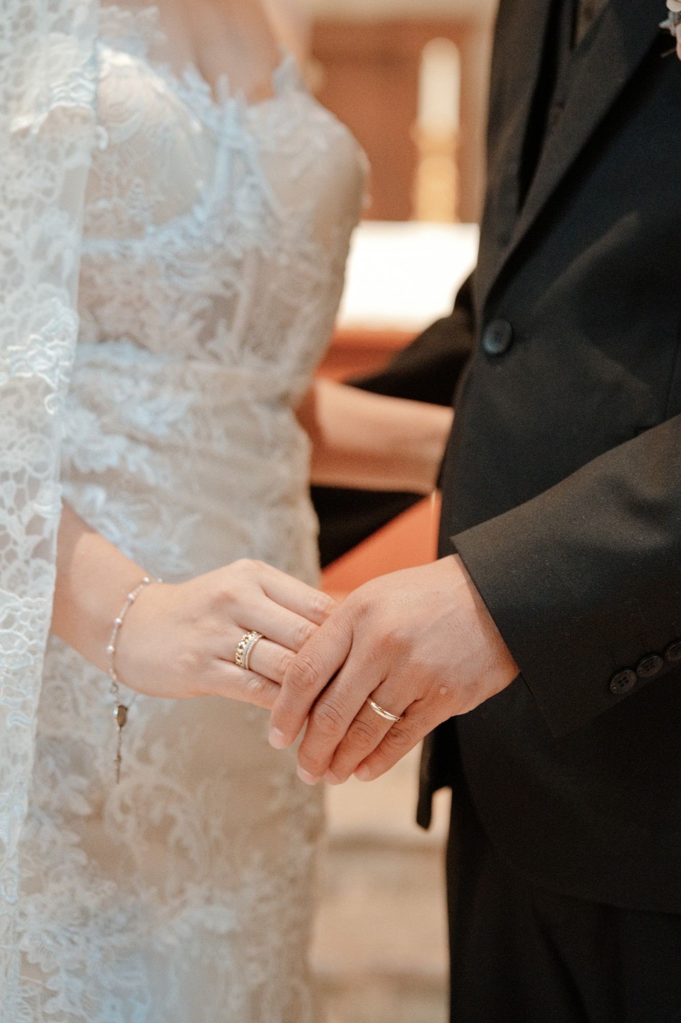 Las manos de los novios tomadas frente al altar, con sus anillos de boda