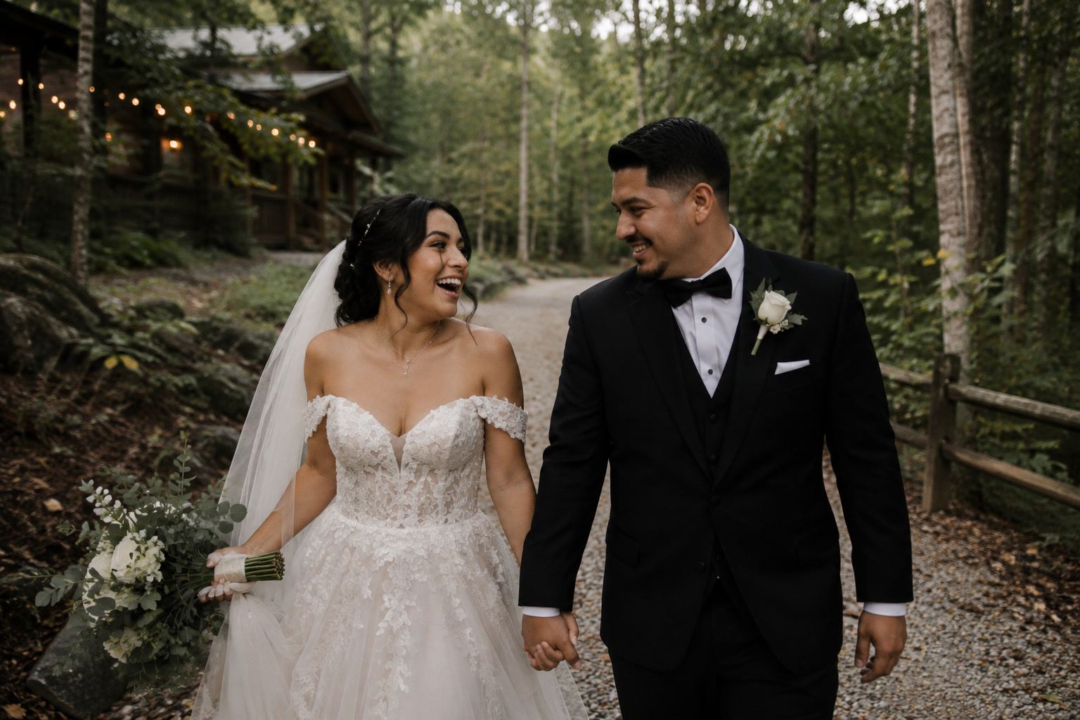 Novios caminando de la mano por un sendero entre árboles el día de su boda